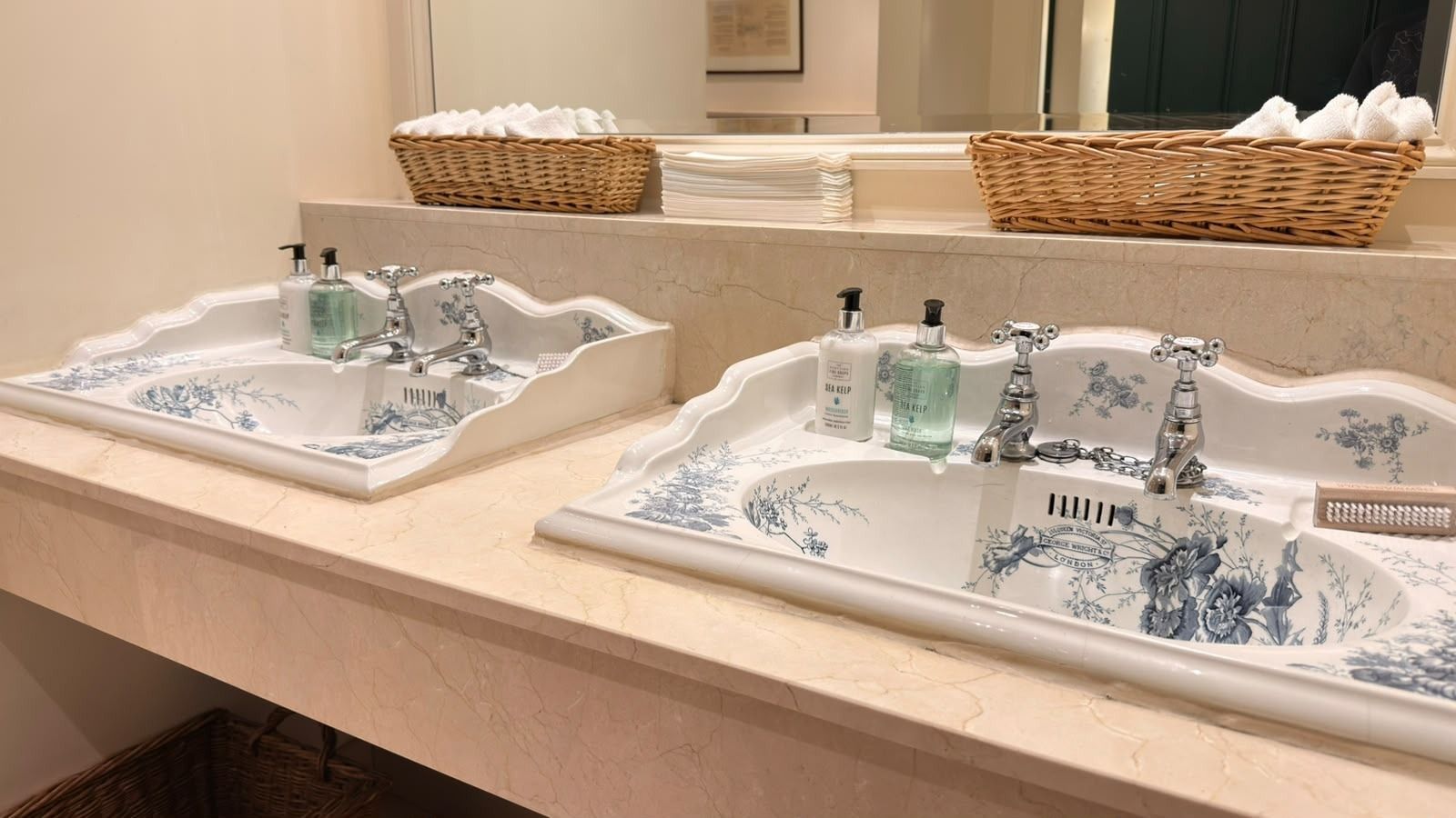 Hand wash and lotion beside blue and white patterned basins in a golf club washroom