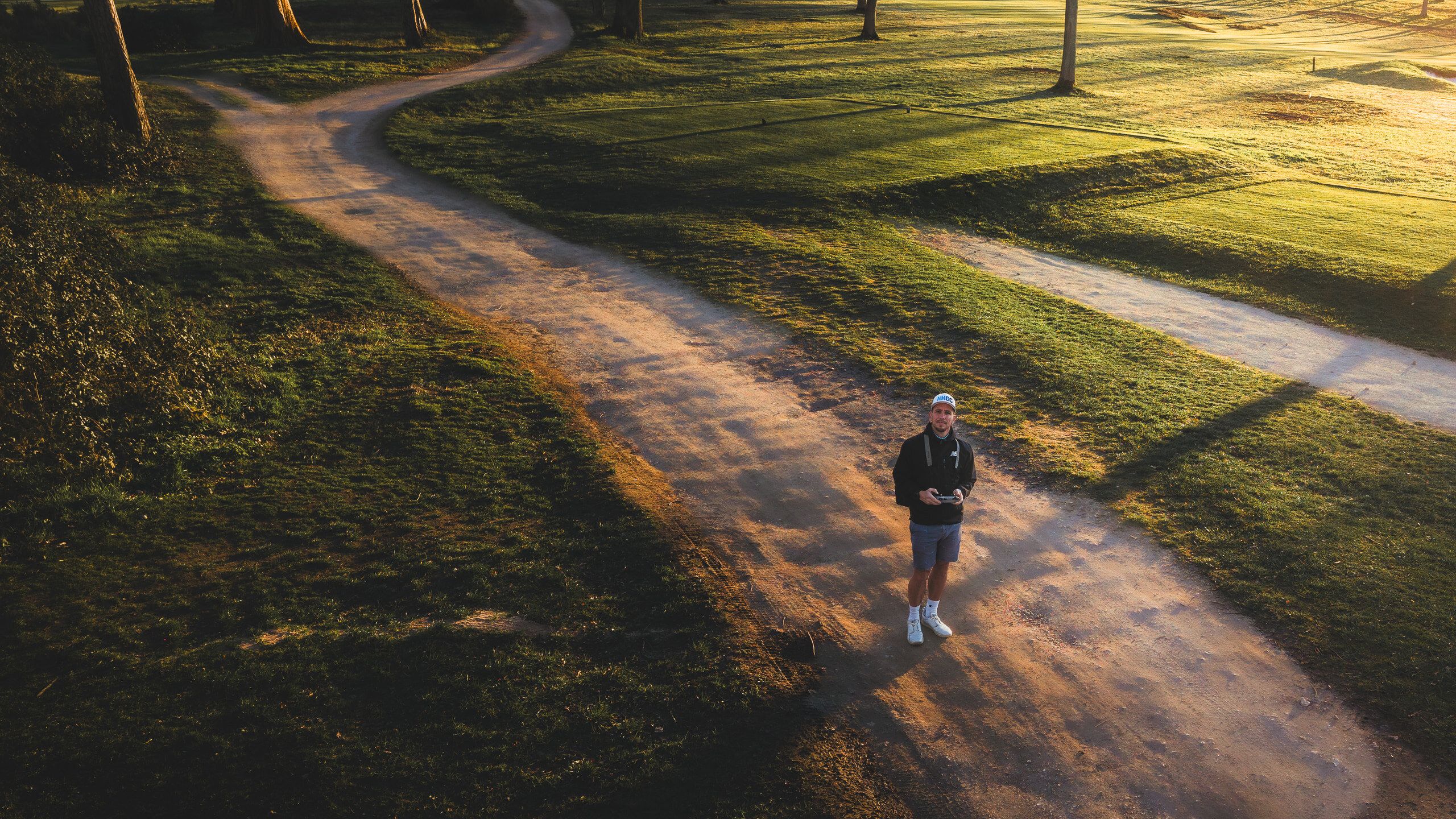 Ollie on a golf course path at sunrise, flying a camera drone