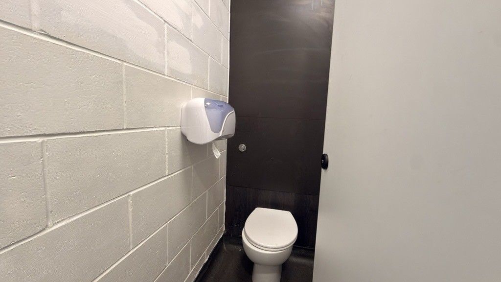 A clean school toilet cubicle with a toilet roll dispenser on the wall
