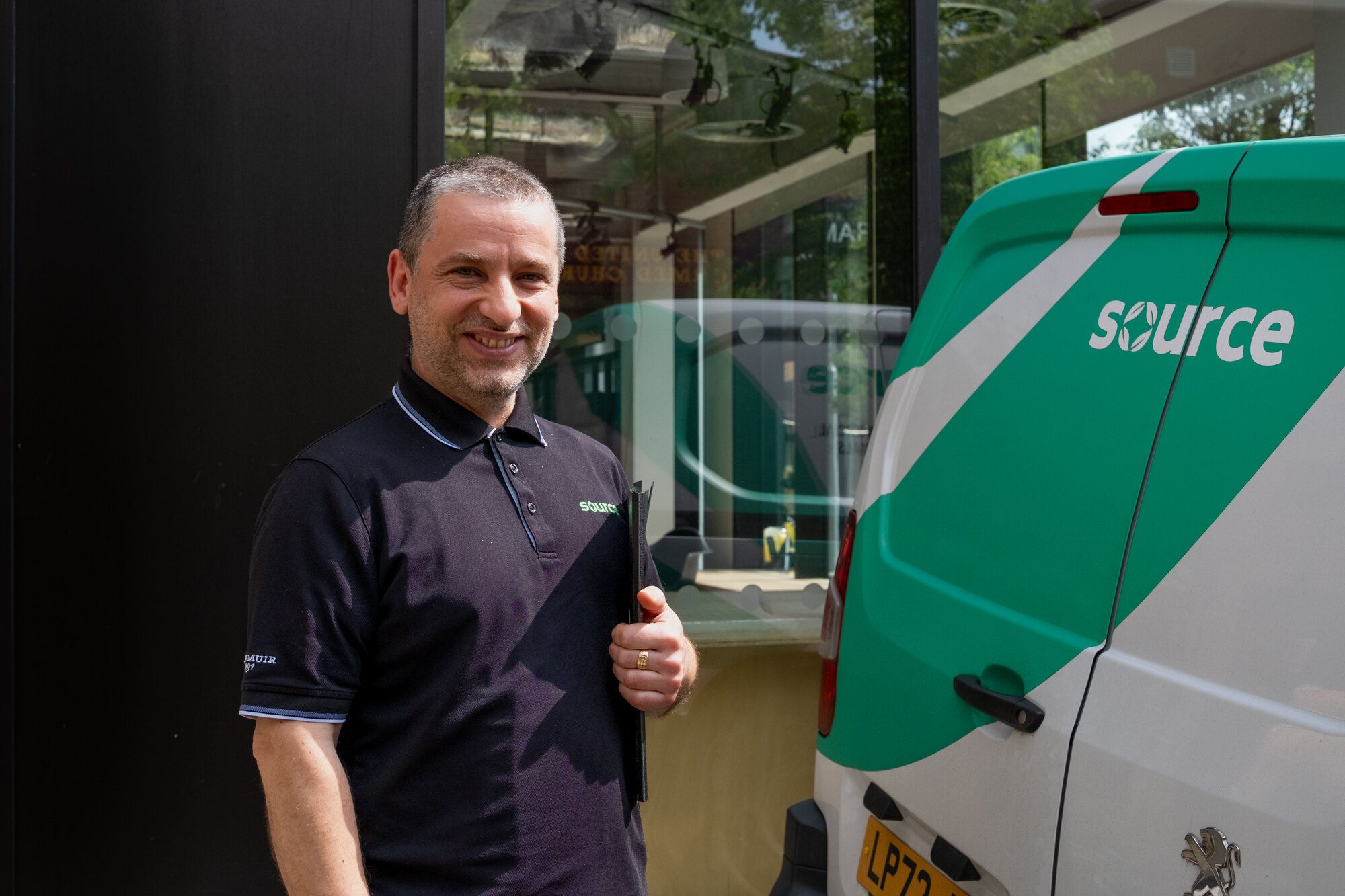 A member of the Source team giving a thumbs up beside a Source van